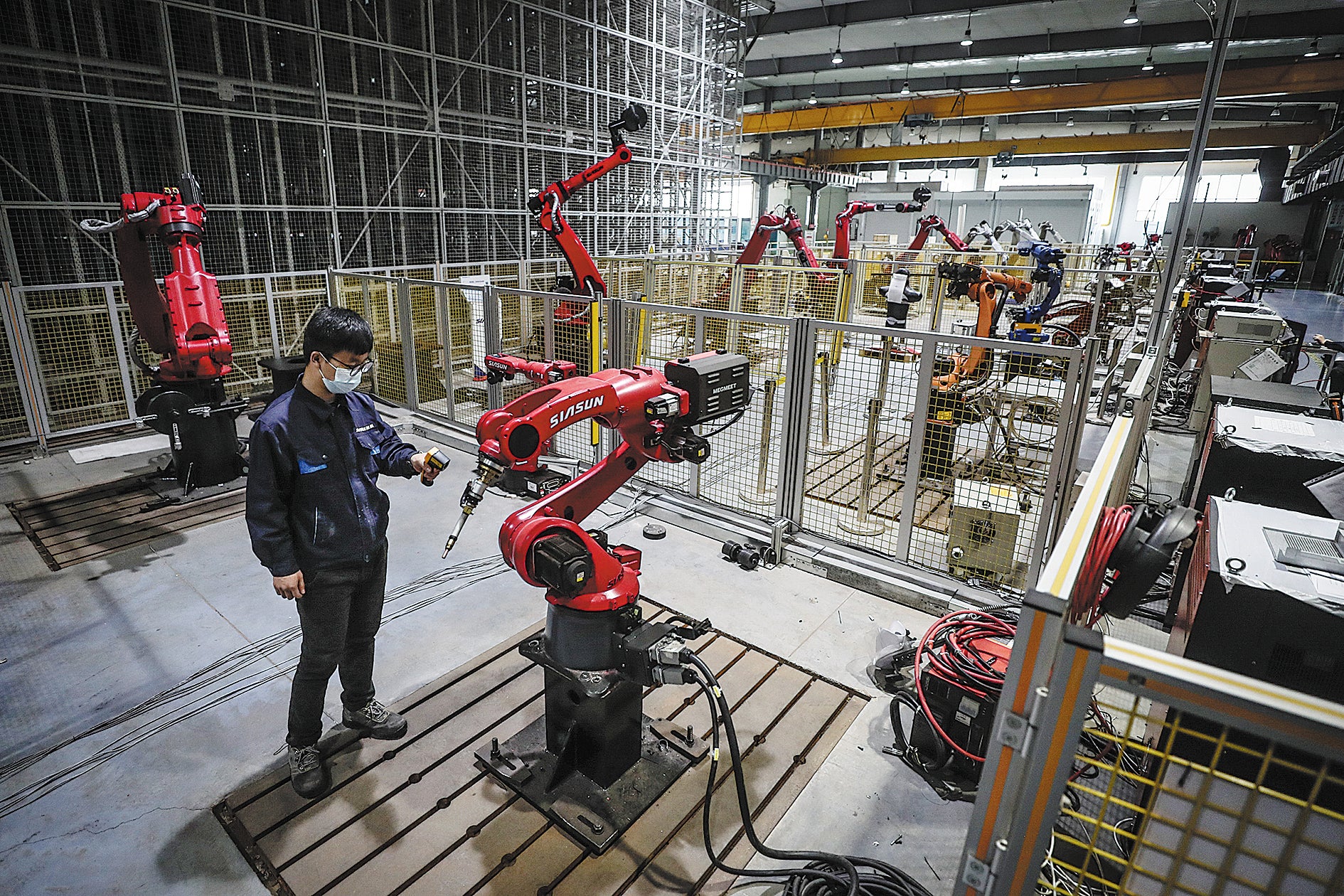 <p>A Siasun technician inspects robots at a workshop in Shenyang, Liaoning province, in April 2022</p>